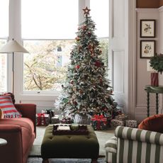 A snow-effect Christmas tree in a living room with decorations from the John Lewis Dawn & Dusk range