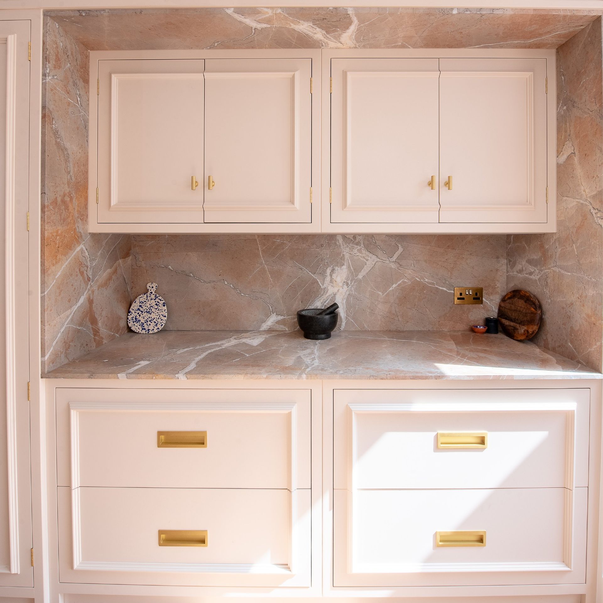 A pink kitchen with a noisette worktop