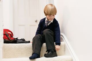 Young boy wearing school uniform and sitting on step