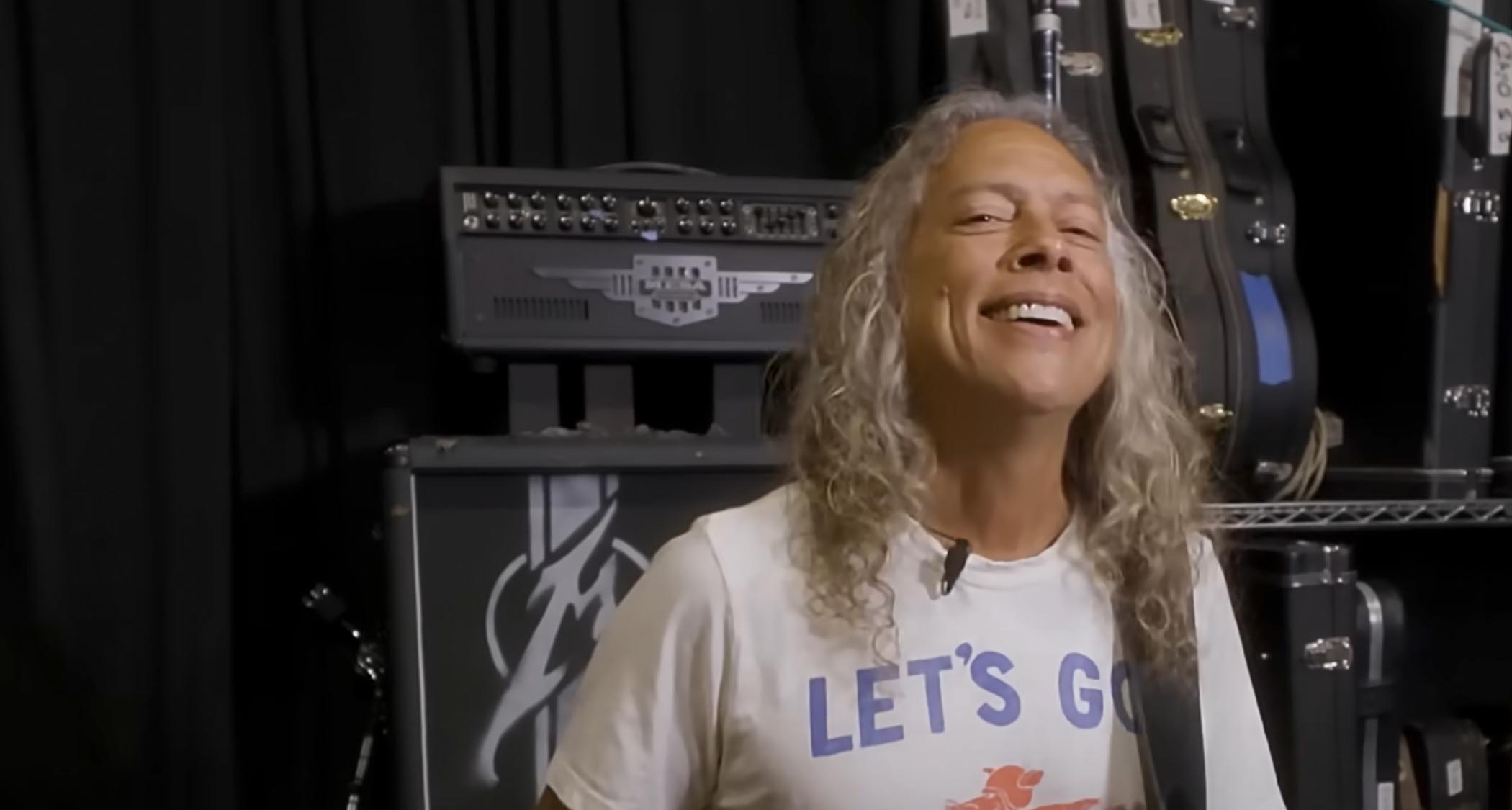 Metallica lead guitarist Kirk Hammett smiles in this still from a YouTube video in which you can clearly see a prototype Mesa/Boogie amp in the background &amp;ndash; the initials &quot;JH&quot; suggest it is a James Hetfield model.