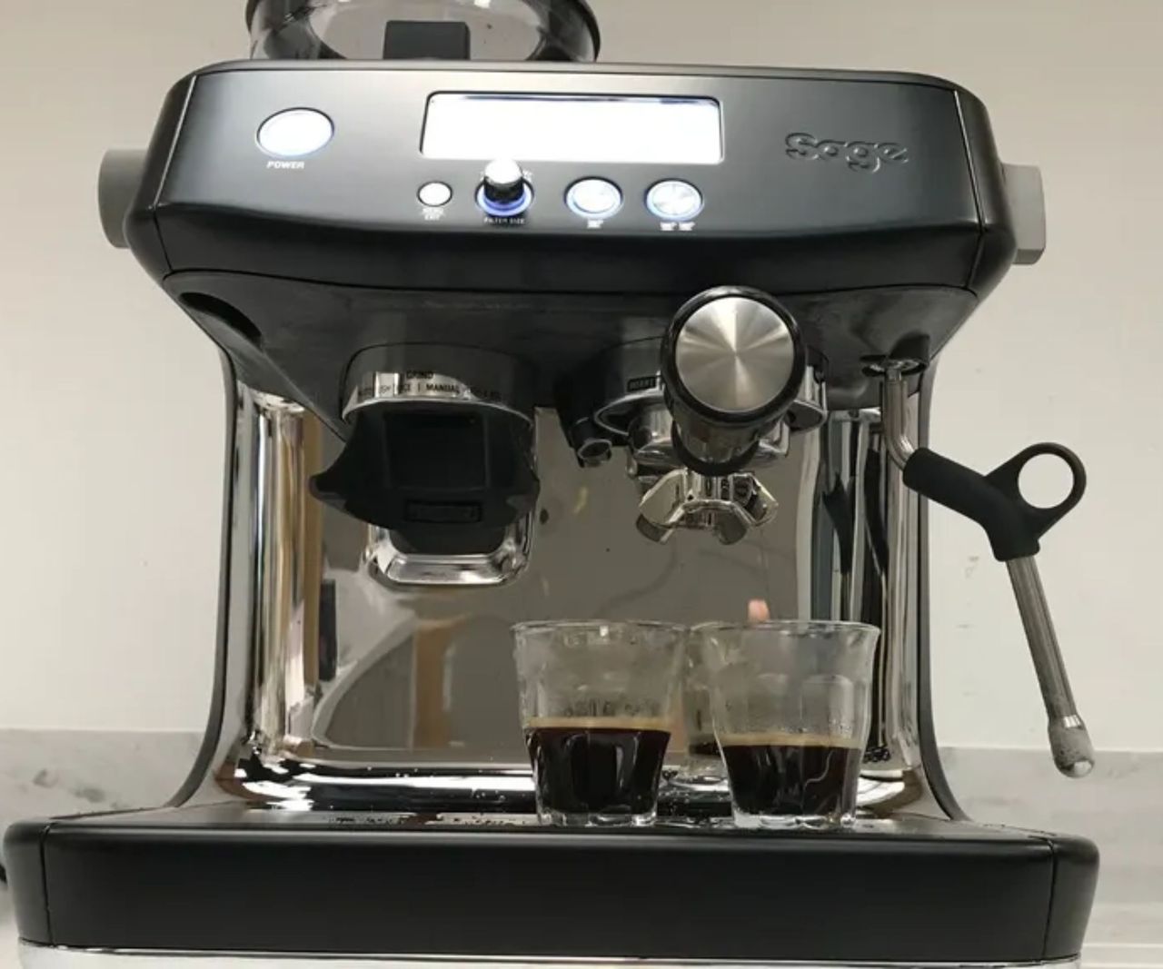 A black Breville Barista pro with two glass shot lasses of espresso on the drip tray.