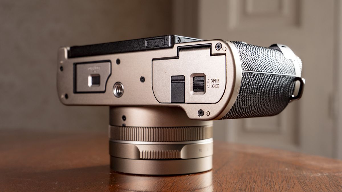 The underside of the Titanium Gold special edition of the Panasonic Lumix L10 compact camera, on an antique wooden table