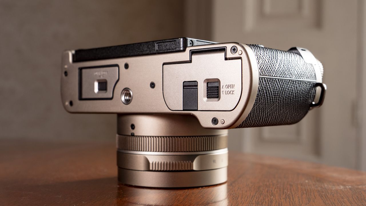 The underside of the Titanium Gold special edition of the Panasonic Lumix L10 compact camera, on an antique wooden table