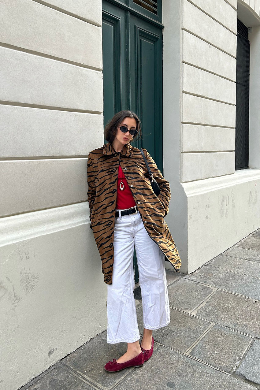 a woman wearing an animal print coat and white pants