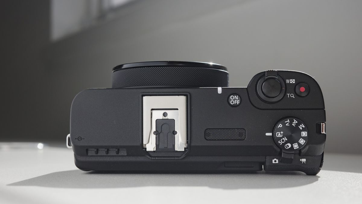 Top plate of the Canon PowerShot V1 compact vlogging camera on a white desk