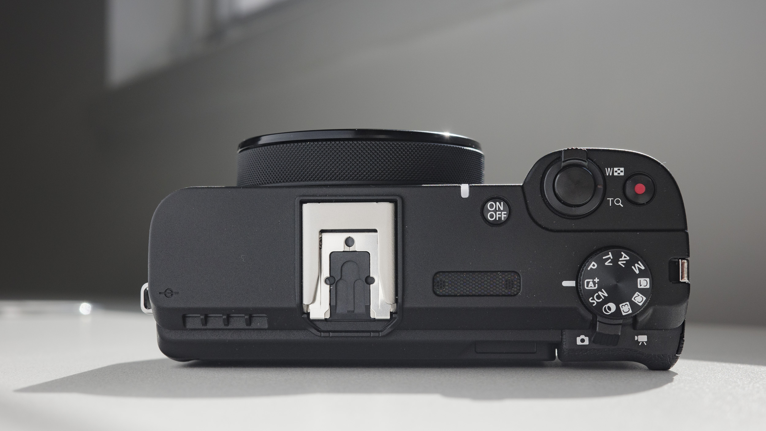 Top plate of the Canon PowerShot V1 compact vlogging camera on a white desk