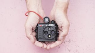 Alfie Tych camera in the hands over a pink surface