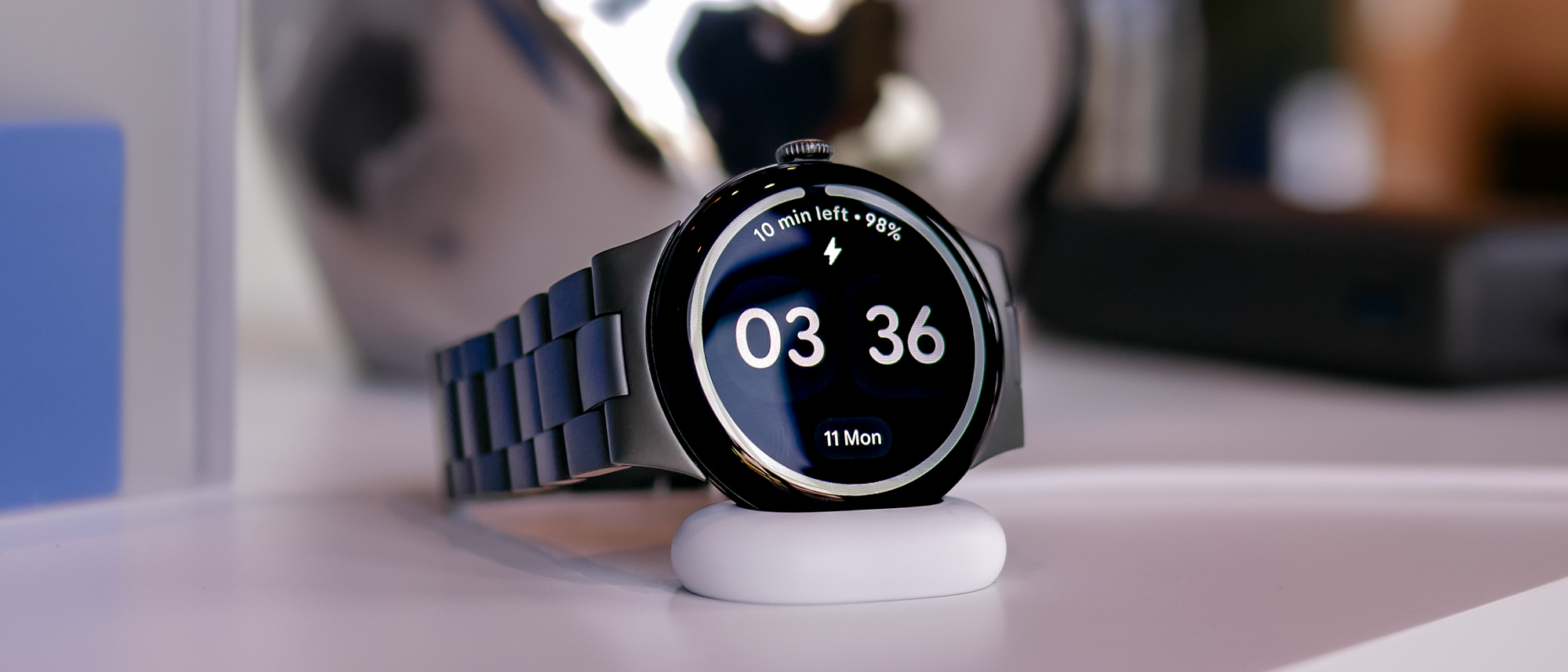 Close-up shot of the Google Pixel Watch 4 in black shown charging on its side