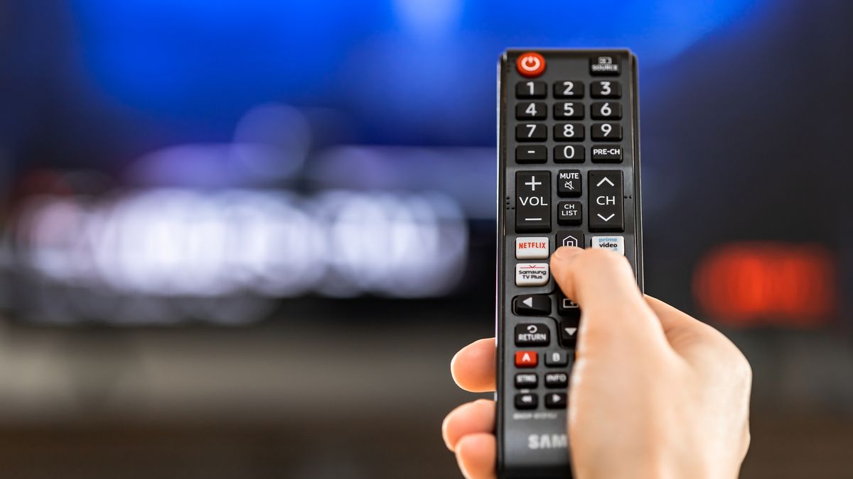 Samsung TV remote being held with one finger on a button