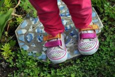 Kid Shoes Standing On A Stepping Stone In The Garden