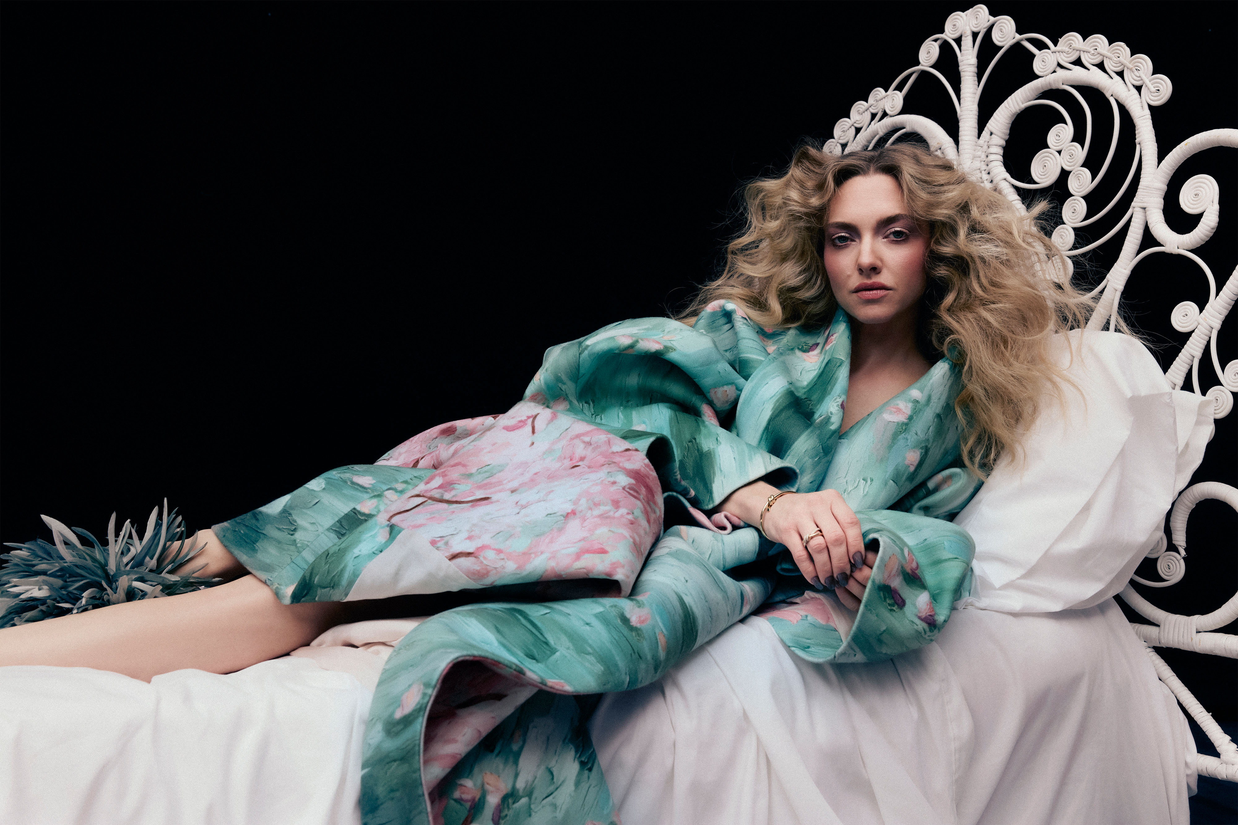 Amanda Seyfried for Who What Wear&#039;s December cover story. She is photographed in a white bed wearing a pastel green and pink oversize coat.