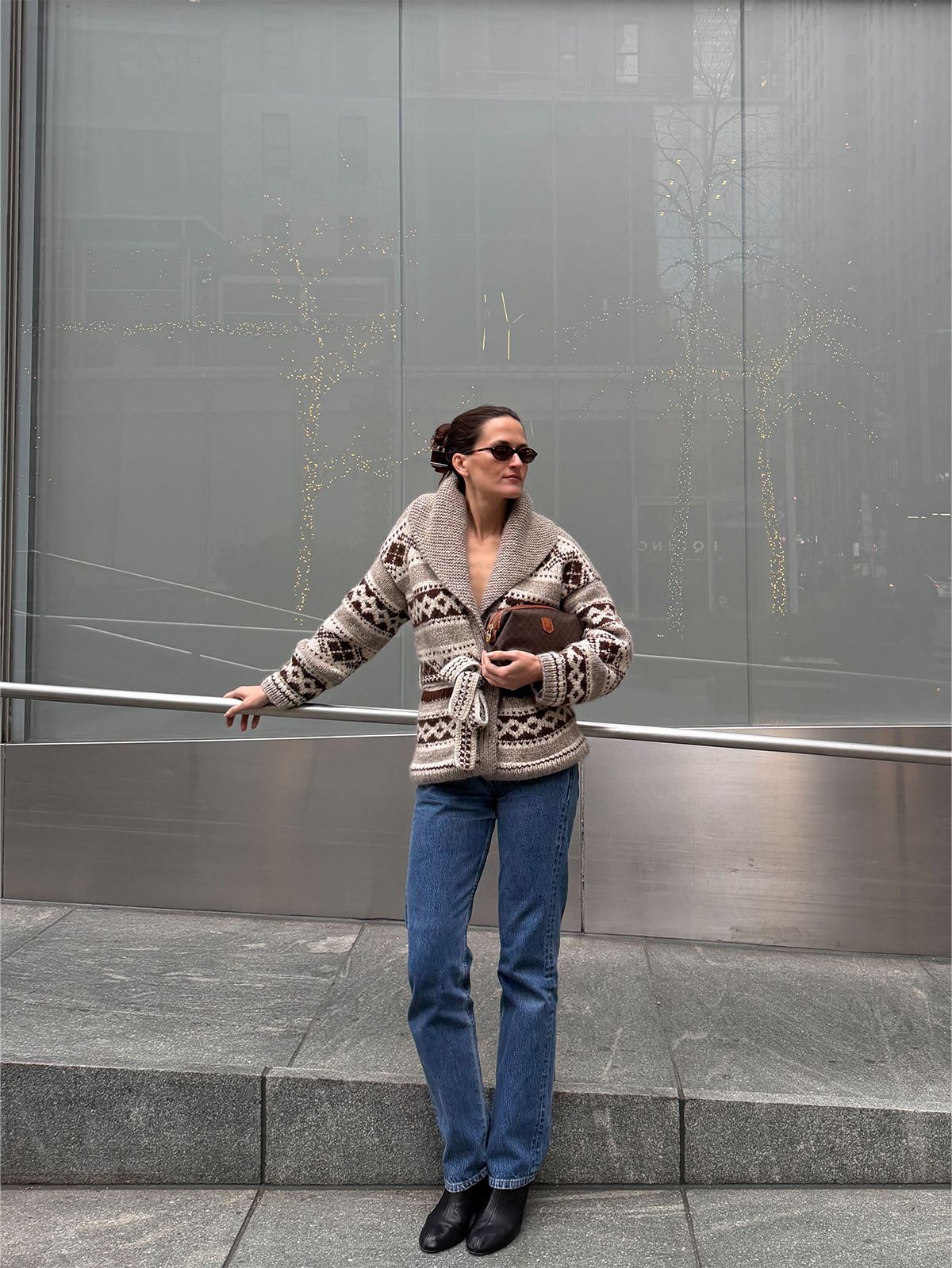 Eliza Huber wearing the Doen Hale Cardigan with jeans and a brown Celine clutch bag.