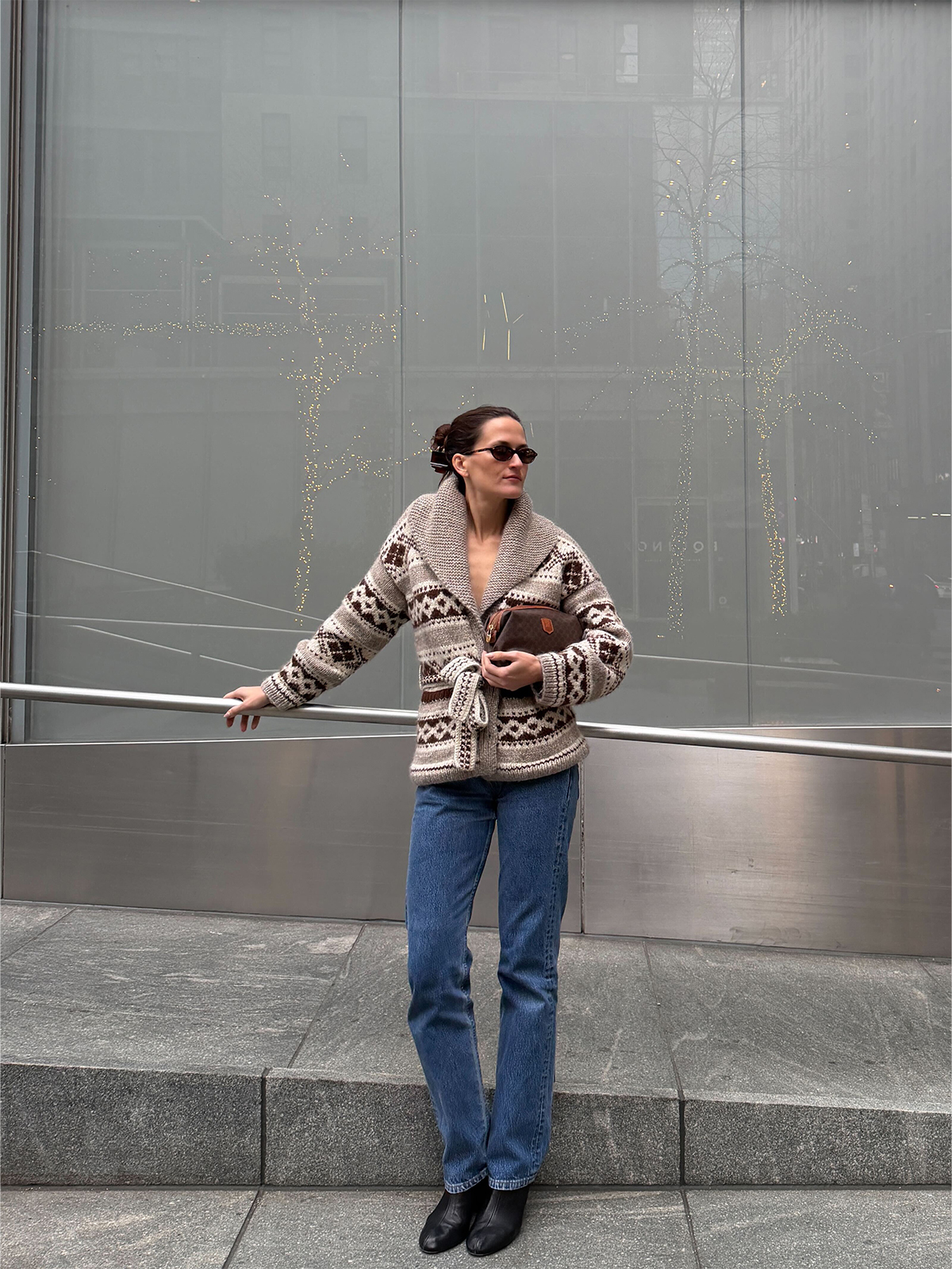 Eliza Huber wearing the Doen Hale Cardigan with jeans and a brown Celine clutch bag.