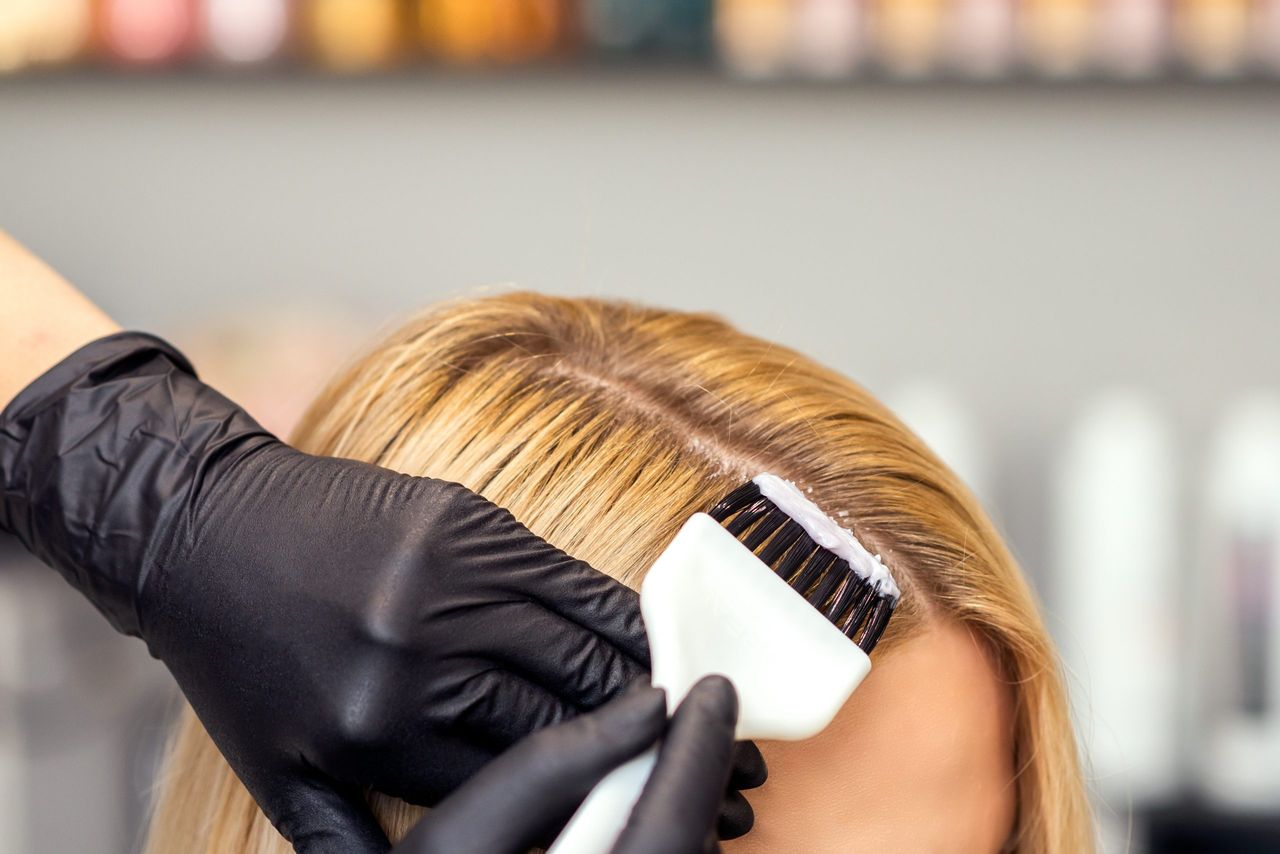 hairdresser putting hair dye on woman&#039;s head