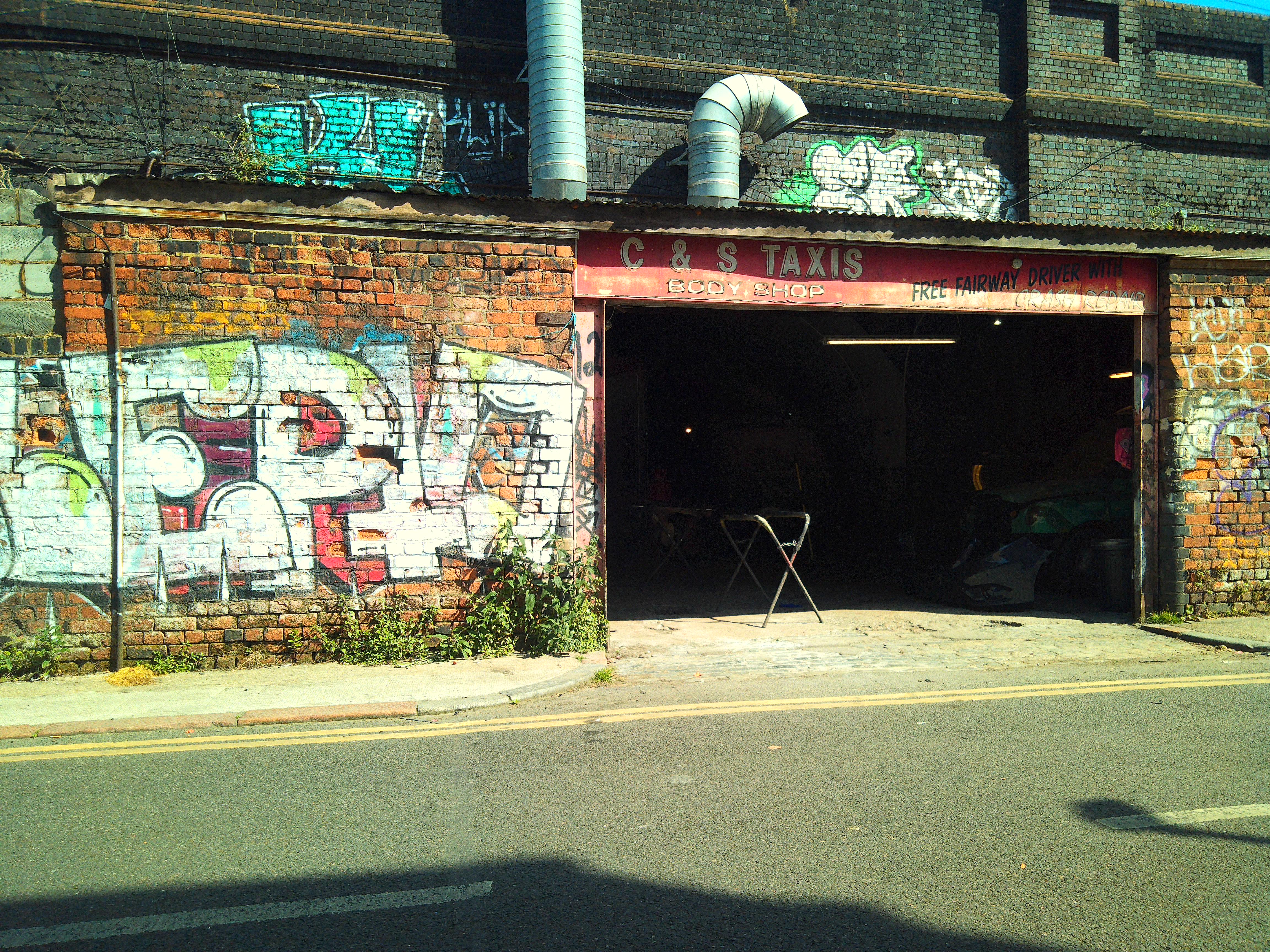 Camp Snap CS-Pro sample image showing garage next to graffiti-covered wall, colors are bright and yellow-toned