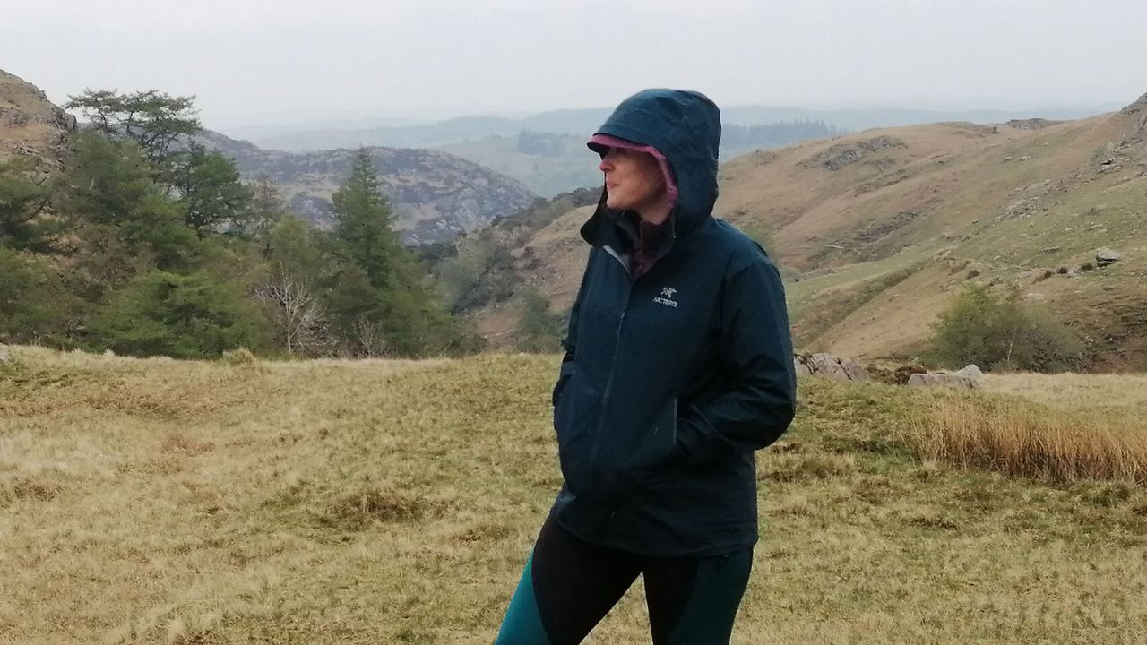 Woman wearing Arc&#039;teryx Beta jacket on a mountainside, in the rain