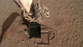 The InSight lander's robotic arm will use its scoop to pin the spacecraft's heat probe, also known as the "mole," against the wall of its hole.