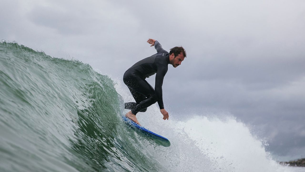 Person surfing/paddle boarding wearing wetsuit