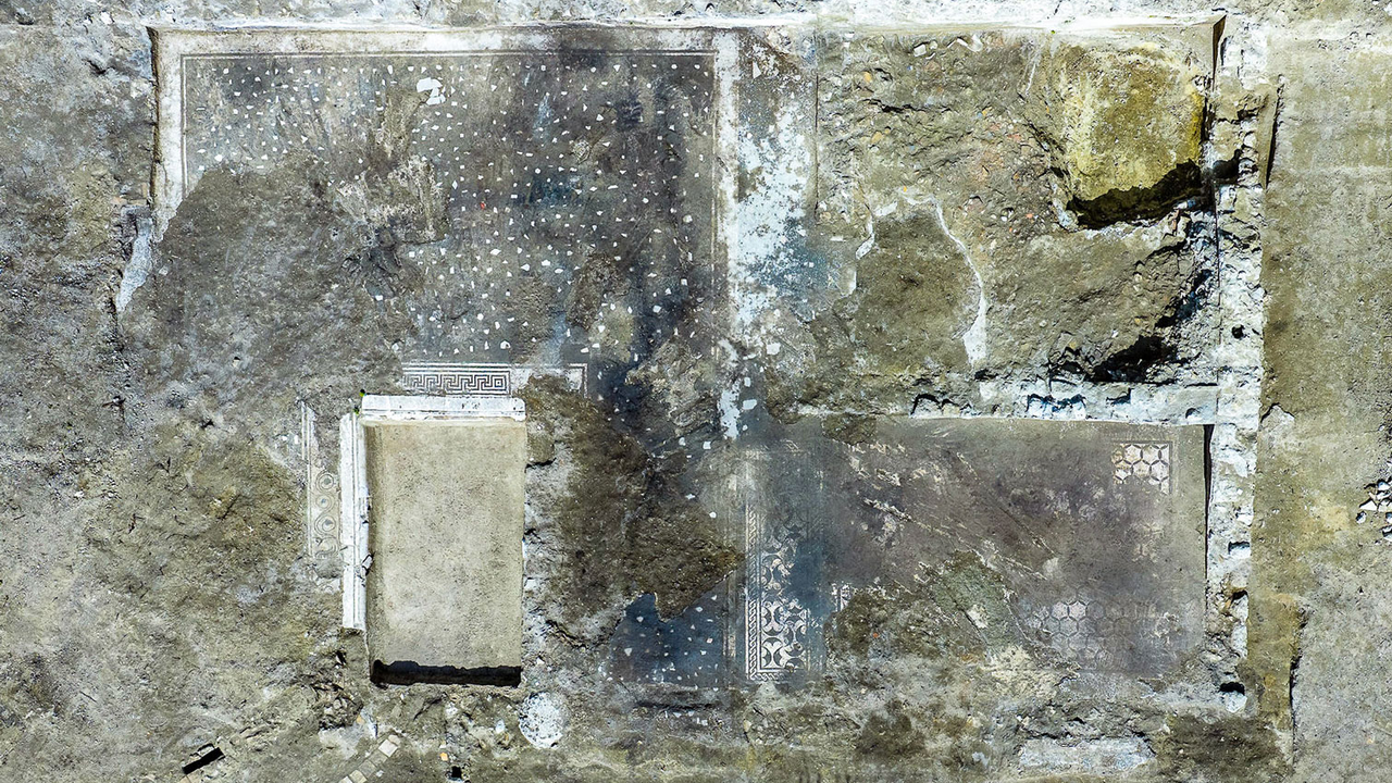archaeologists work at an ancient Roman site revealing mosaic floors and frescoed walls of a villa