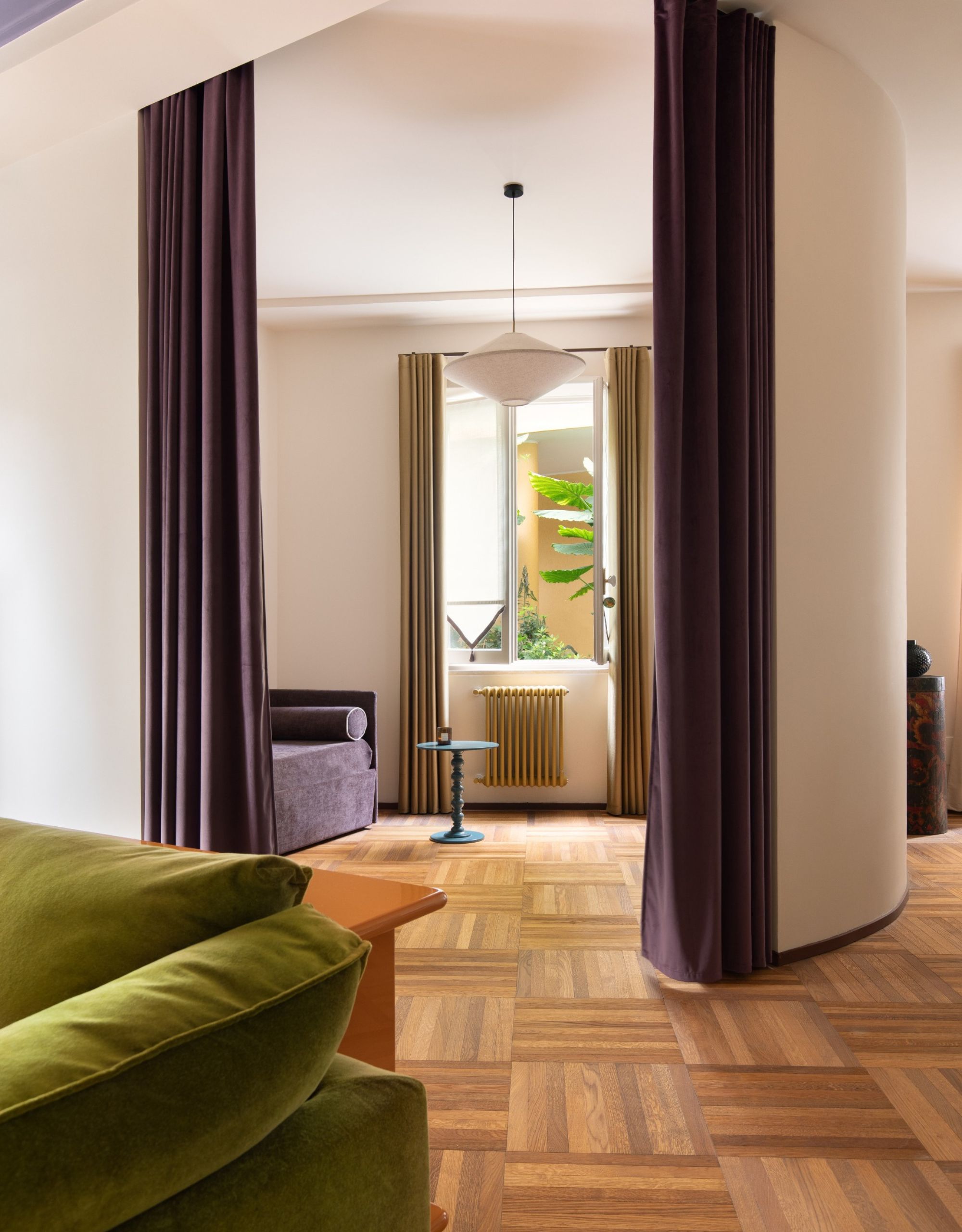 A round curved wall with dark purple curtains as doors lead to a guest bedroom