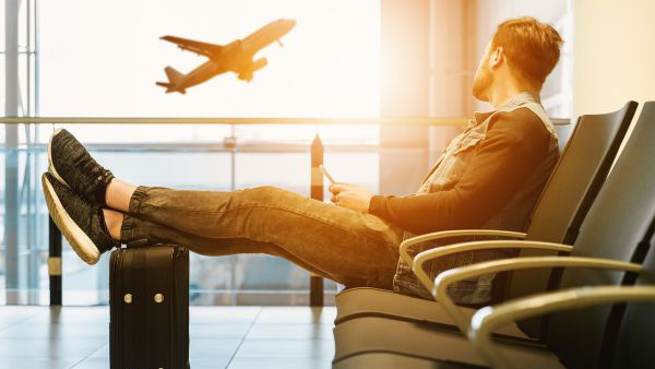 Man waiting for his flight to arrive with his luggage nearby