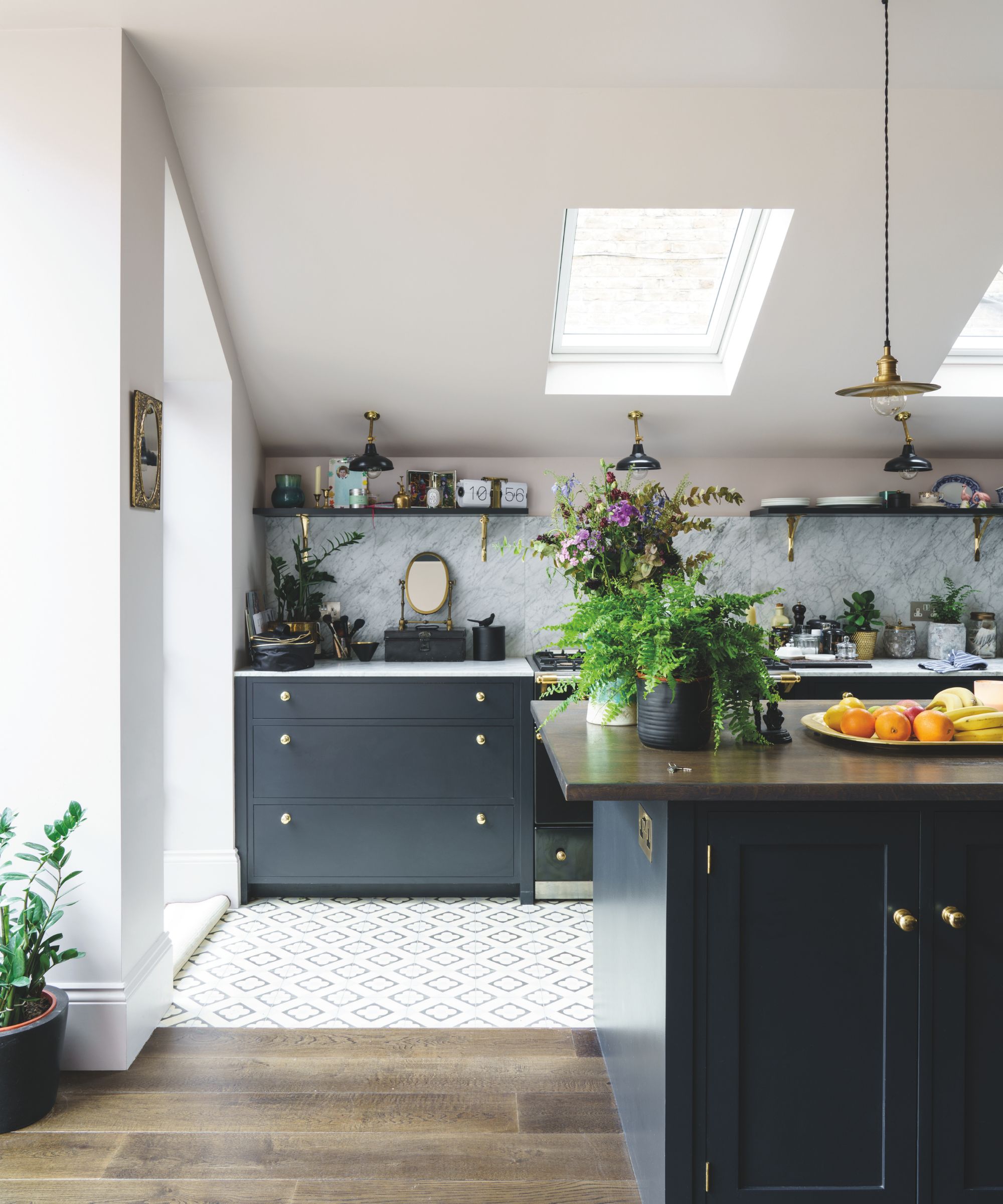 Kitchen with white walls and skylights, tiled and wood floor, dark black painted cabinetry and low pendant light
