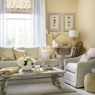 yellow and grey living room with prints, armchair and rustic look