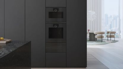 A kitchen in all-black, with neutral white flooring, and a double oven in-built