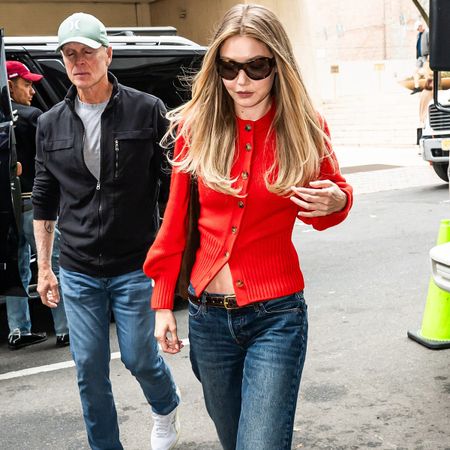 Gigi hadid wears a red sweater and low-rise jeans.