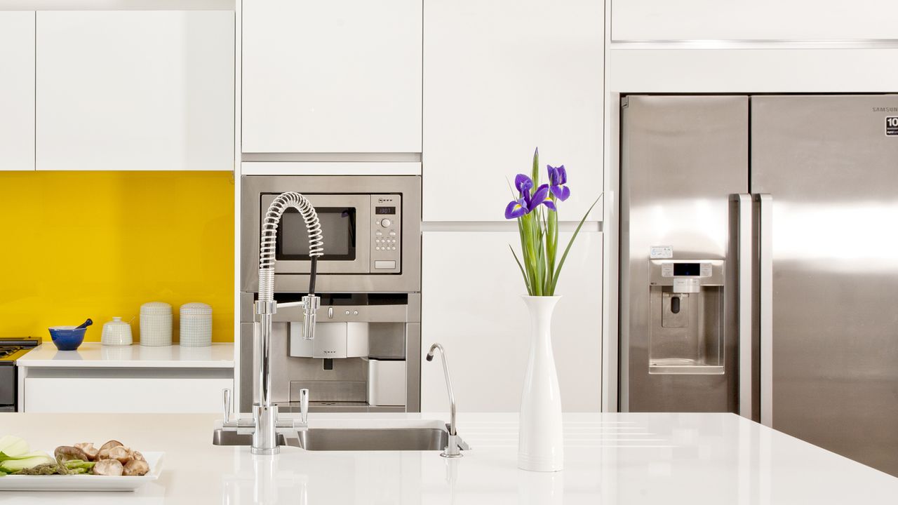 A white kitchen with a yellow splashback and American-style fridge freezer