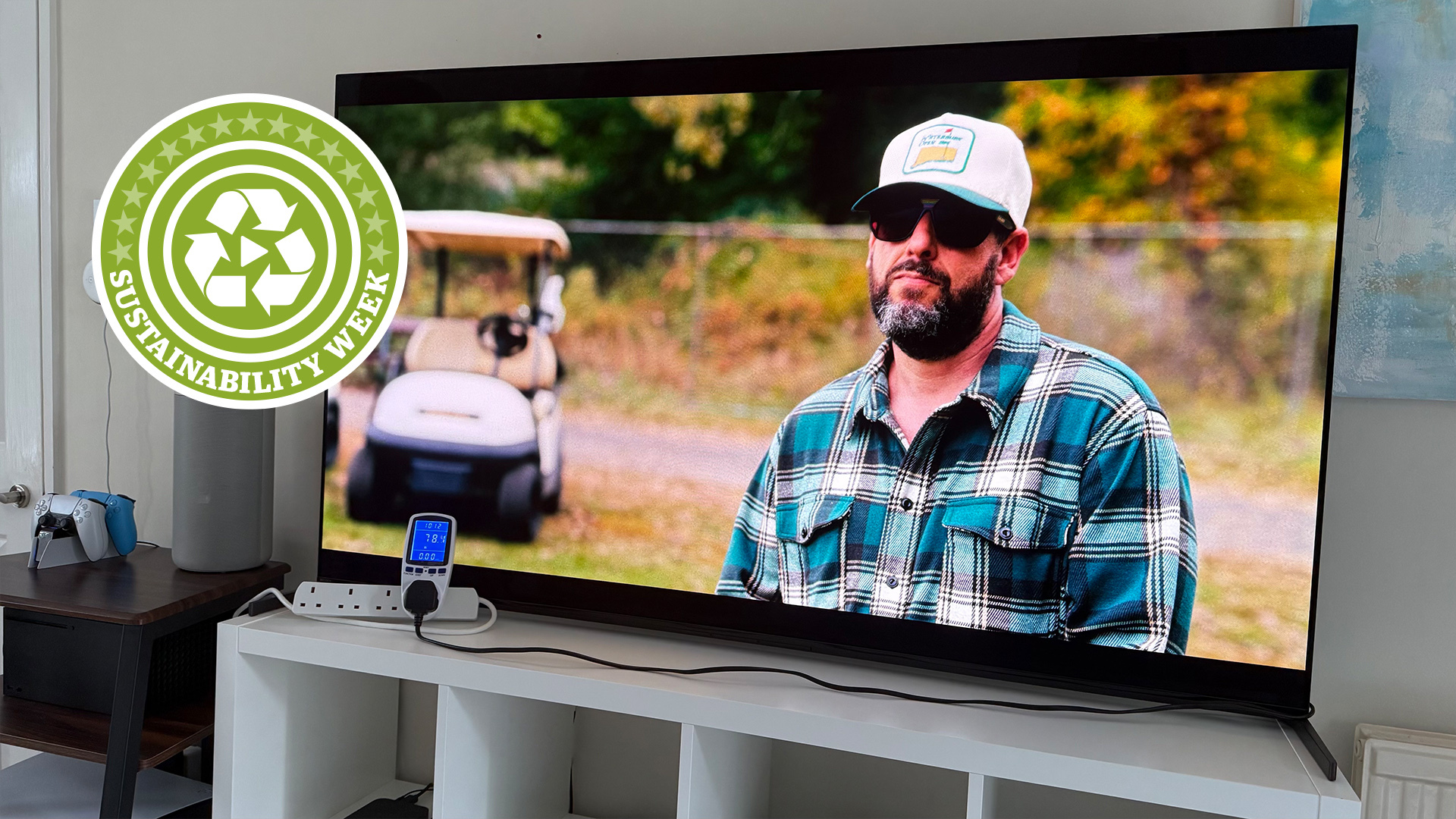 The 65-inch Sony A95L OLED TV pictured on a white shelf. On the screen is a still of Adam Sandler in Happy Gilmore 2, and in the corner of the photo is a green badge that says &#039;Sustainability Week&#039;.