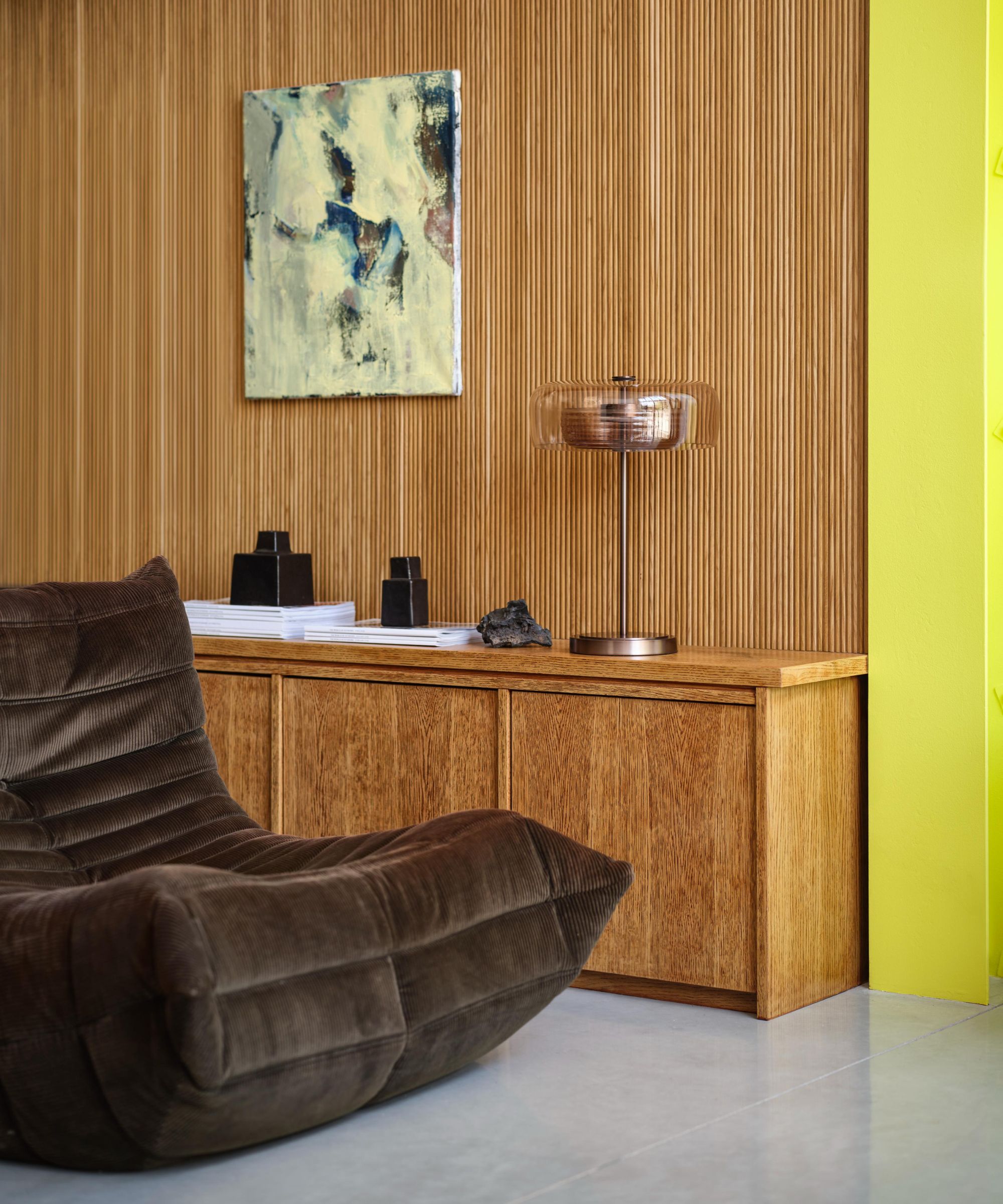 Paneled wall with mid century low cabinets and brown Togo chair