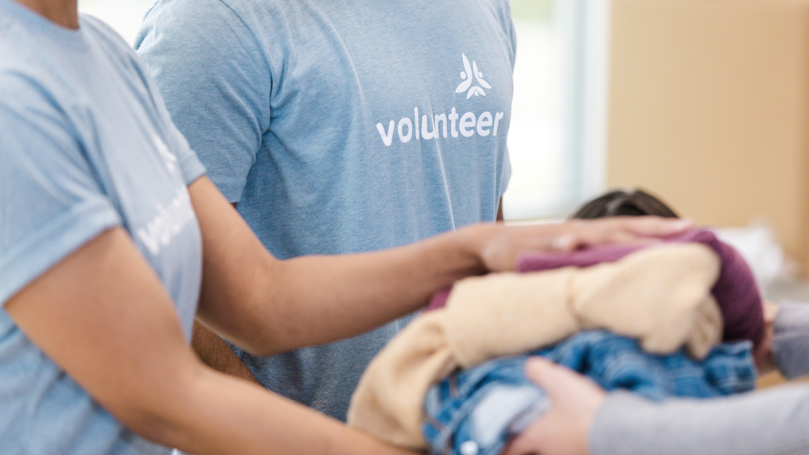Two volunteers hand over donated clothing.