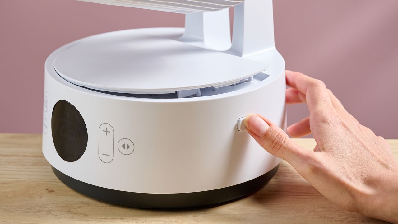 A woman is pressing the release button for the cover of the battery compartment.