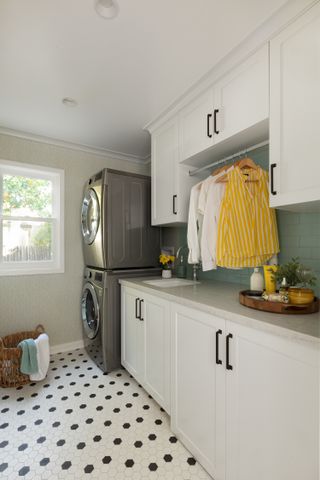laundry room with hex tiles, white units, washers, wallpaper, tiled splash back, hanging area for clothes