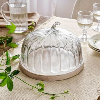 Glass Pumpkin Cloche with Wood Pedestal on a tablecloth.