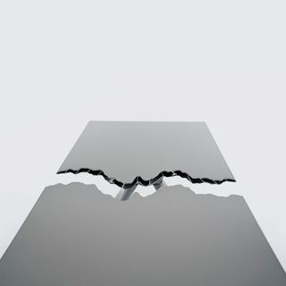 An overhead shot of a grey table top that has been split in two with a tear in the middle.