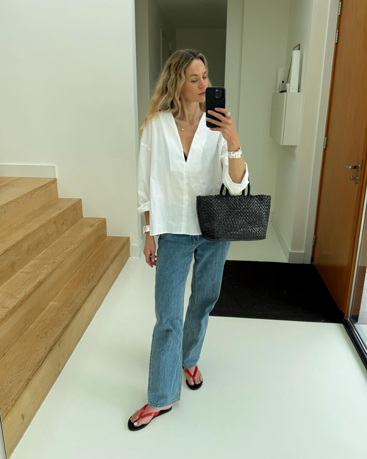 anouk yve wears a white shirt, blue straight jeans and red flip flops