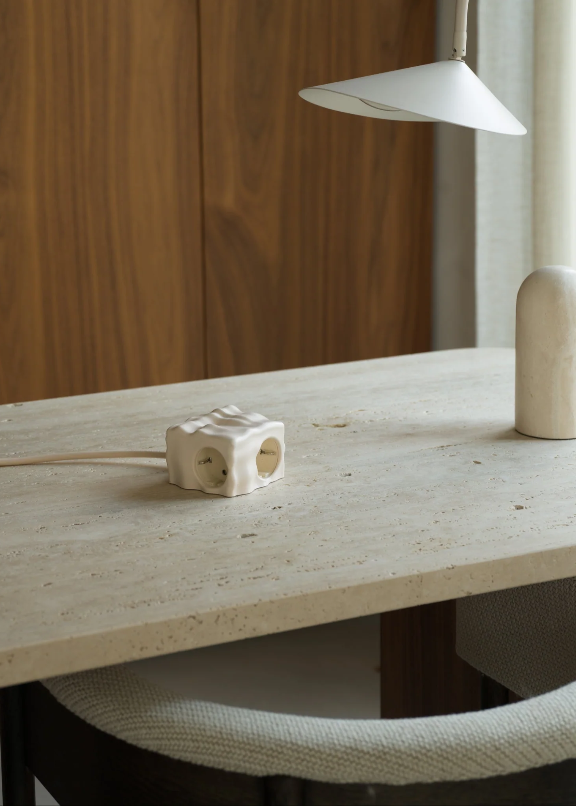 A stone desk with a textured adapter by an ivory table lamp
