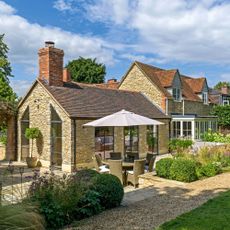 How to maintain your roof cotswold yellow stone period home with tiles roof and patio area with patio furniture and parasol