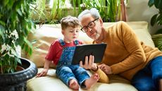 Curious little boy looking at device screen with his granddad, play, entertainment, watching, imagination