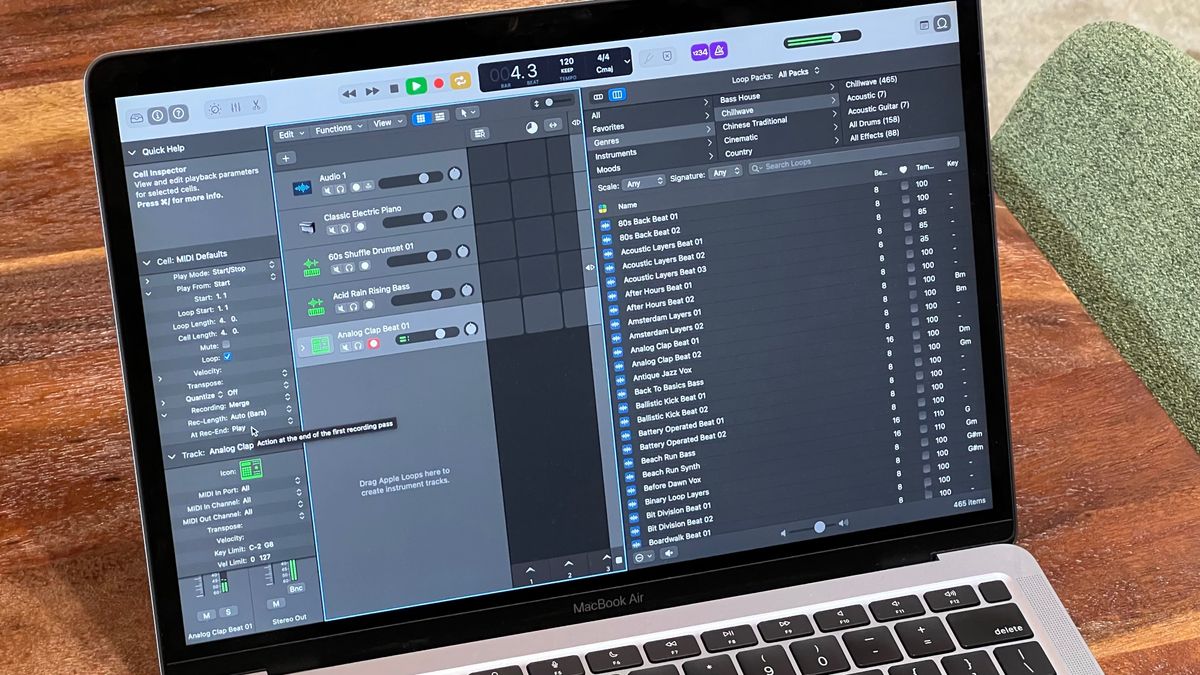 Photograph of Logic Pro open on a MacBook Air that&#039;s sitting on a wooden table. A green chair is visible off to the right.