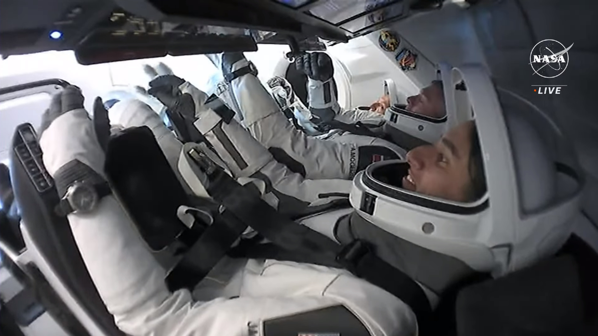 Top Stories Tamfitronics three astronauts in white spacesuits with open helmet faceplates sit inside a SpaceX capsule in orbit