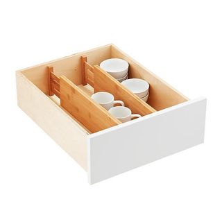 Bamboo wooden extendable drawer dividers in a single wooden drawer with a white front. Separating small mugs. 