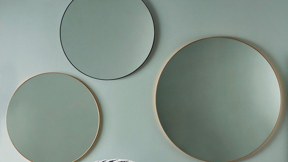 3 round mirrors on green wall in hallway