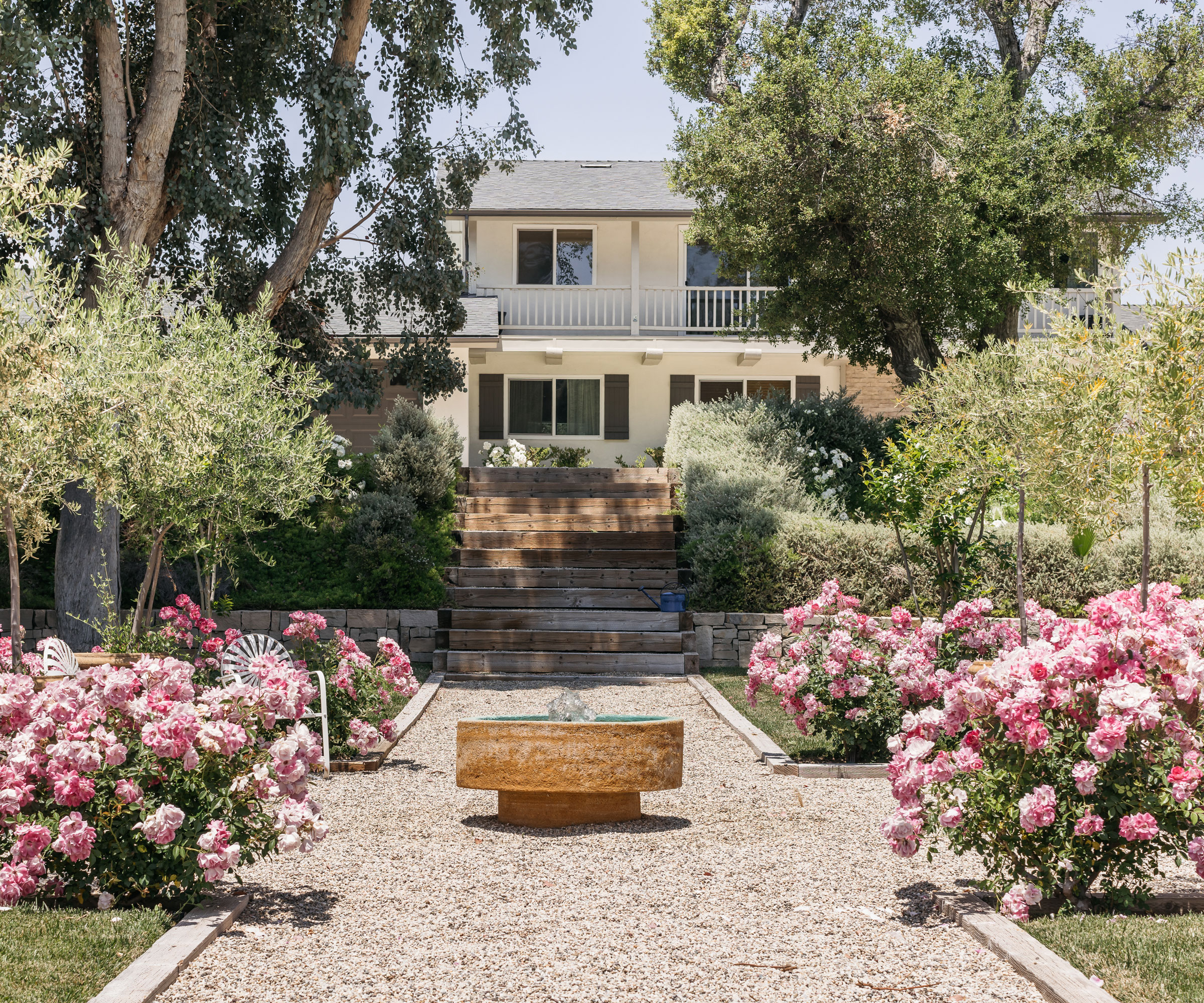 sunken garden design featuring gravel landscaping, trees and rose bushes, with pockets of lawn