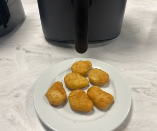 Quorn nuggets on a plate in front of the Cosori Pro LE Air Fryer.