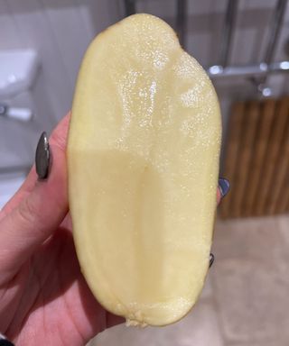 A hand holding a potato cut in half