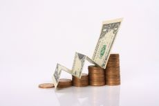 Stack of coins and a dollar bill representing growing wealth.