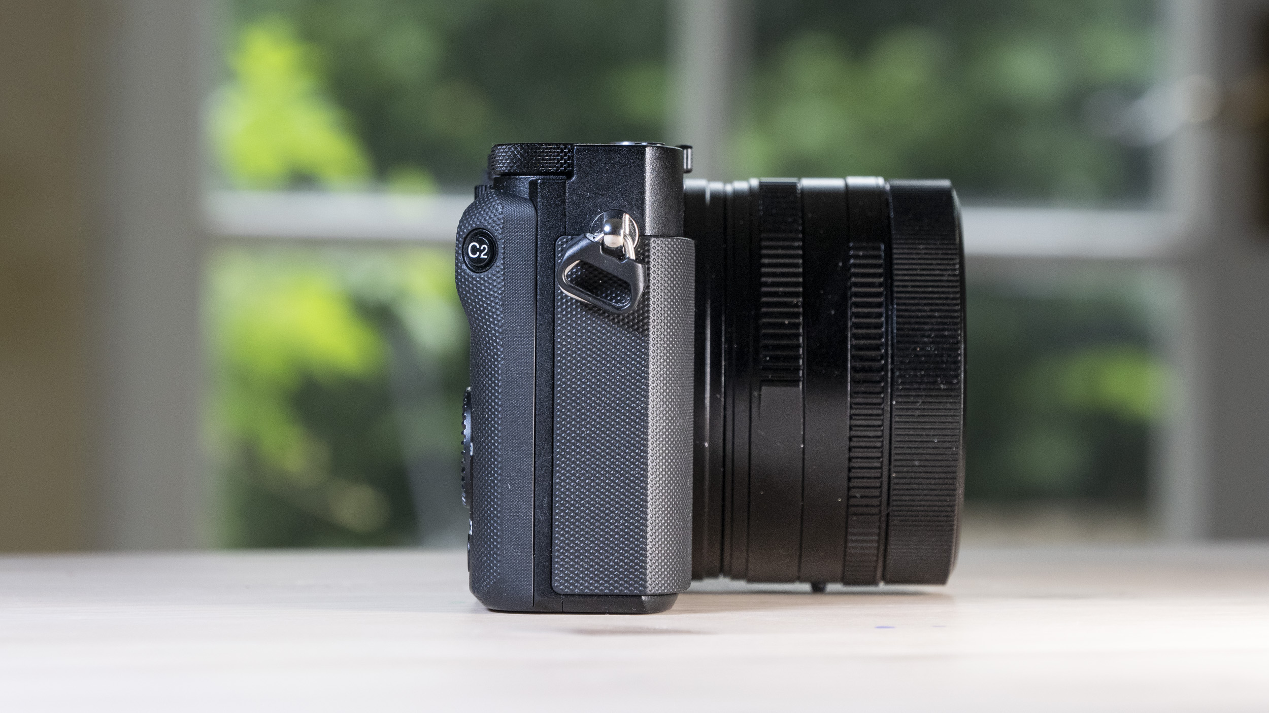 Side profile of the Sony RX1R III compact camera, on a wooden table